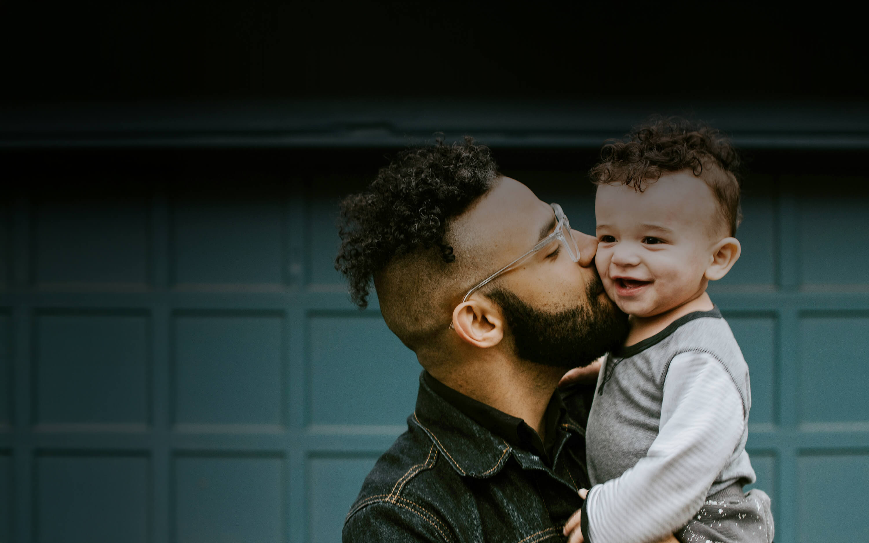 Adult male kissing the cheek of an infant