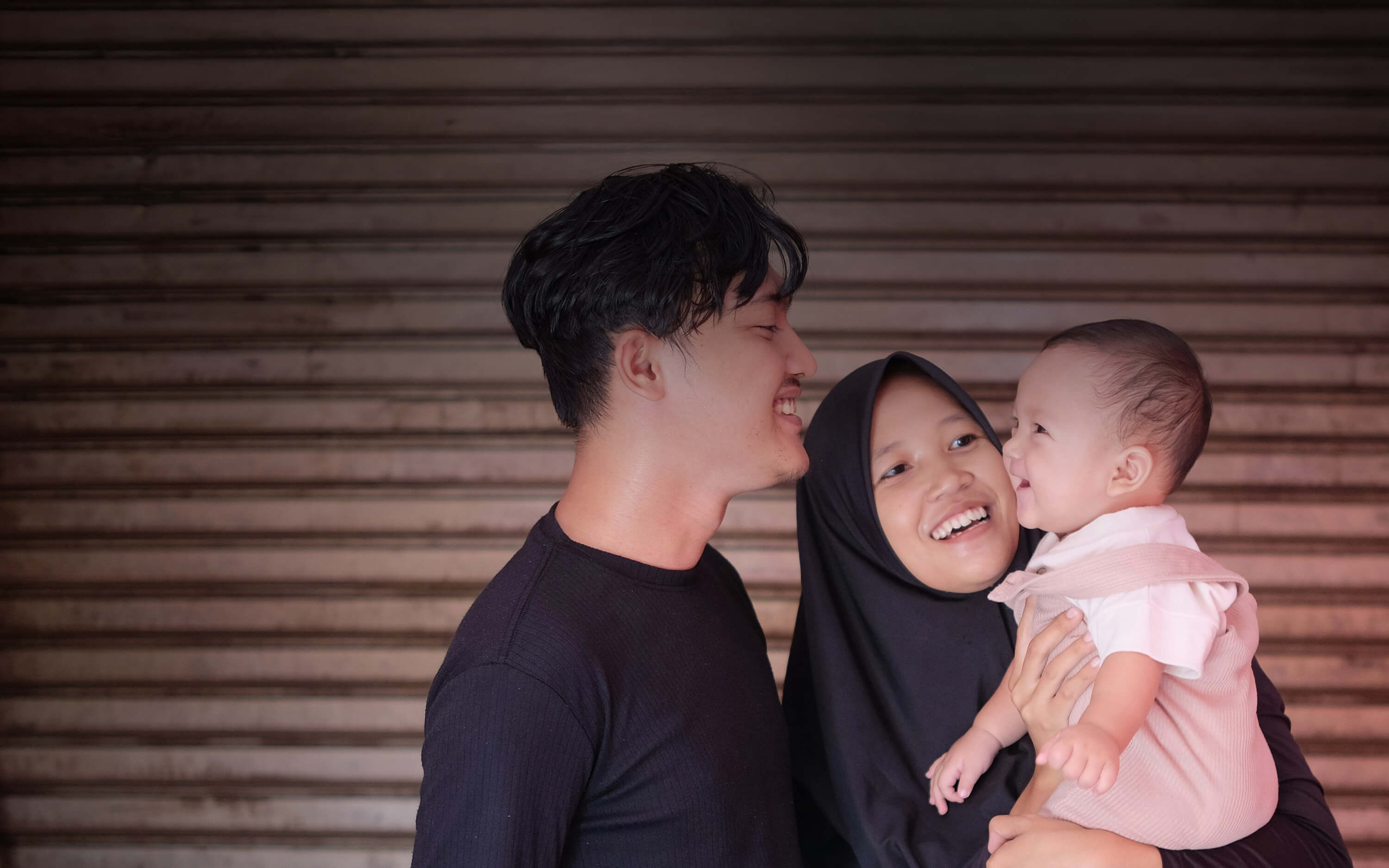 Woman holding a baby with man next to her and all are smiling