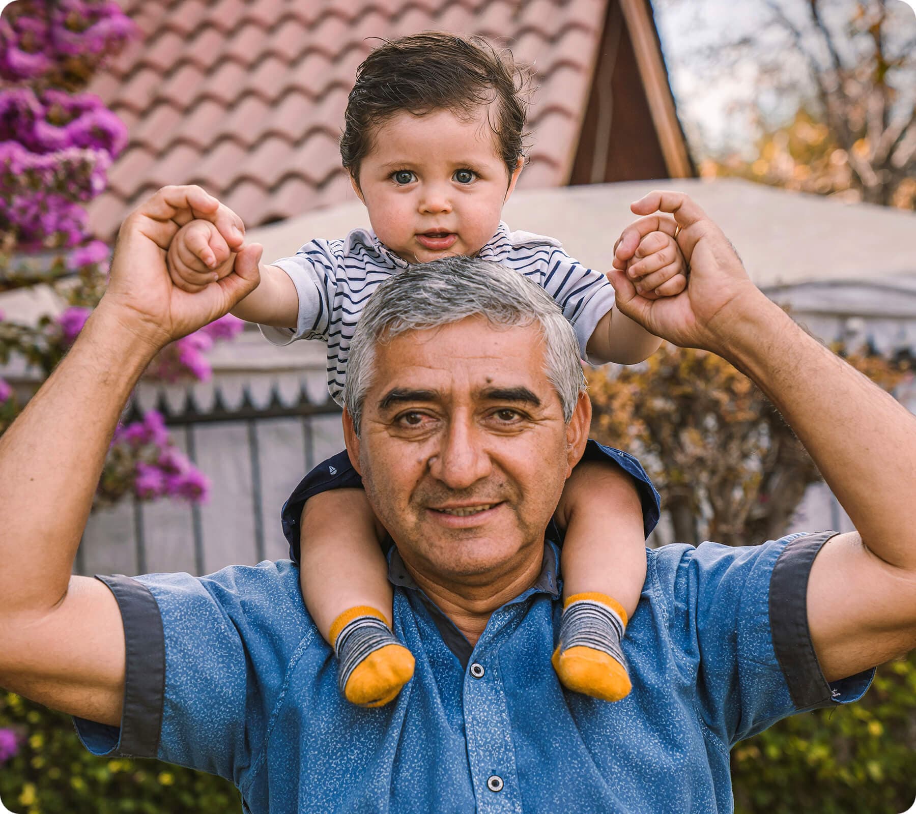 Older man with a baby sitting on his shoulders for a shoulder ride