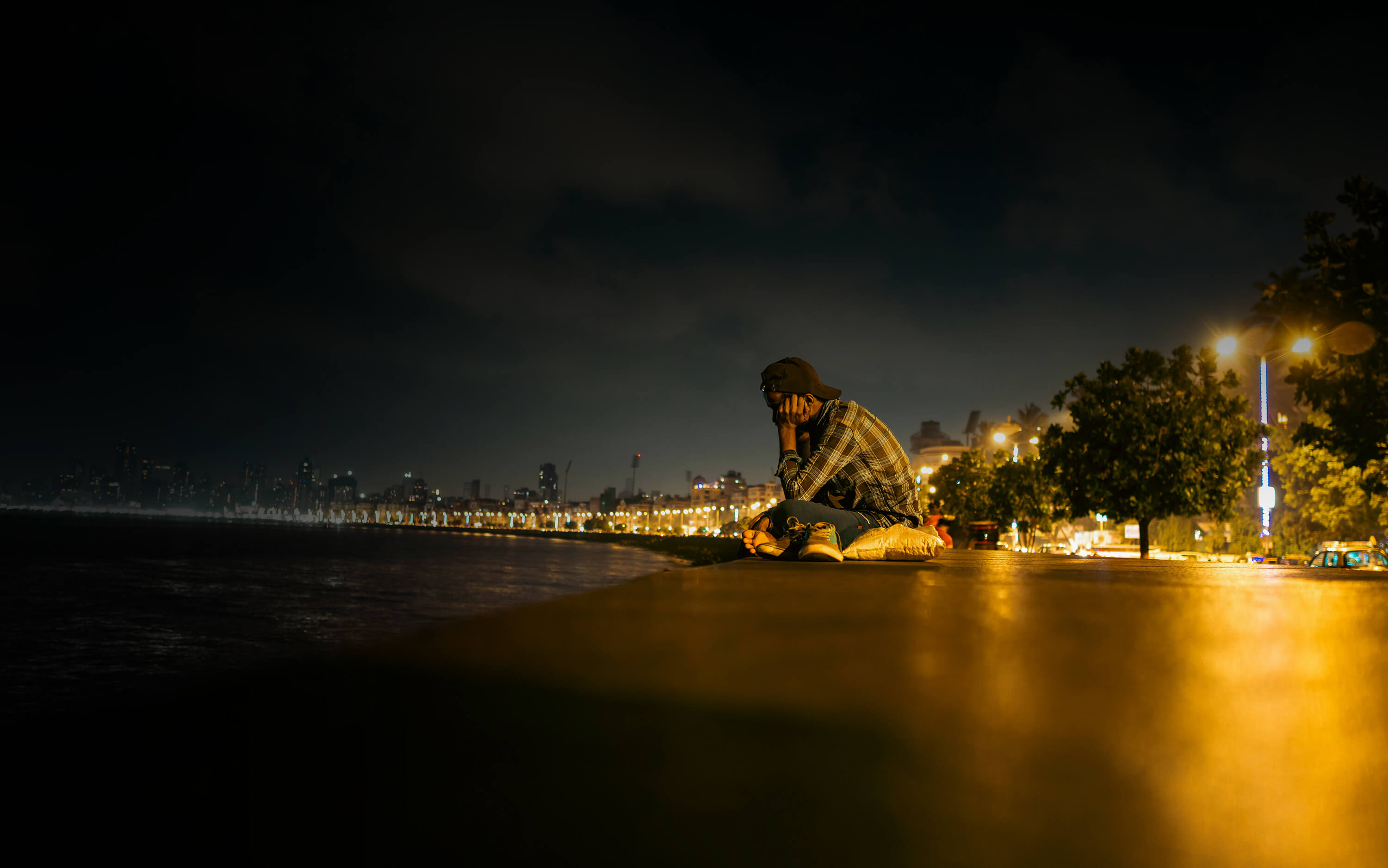 Man sitting outdoors by the water at nighttime looking down