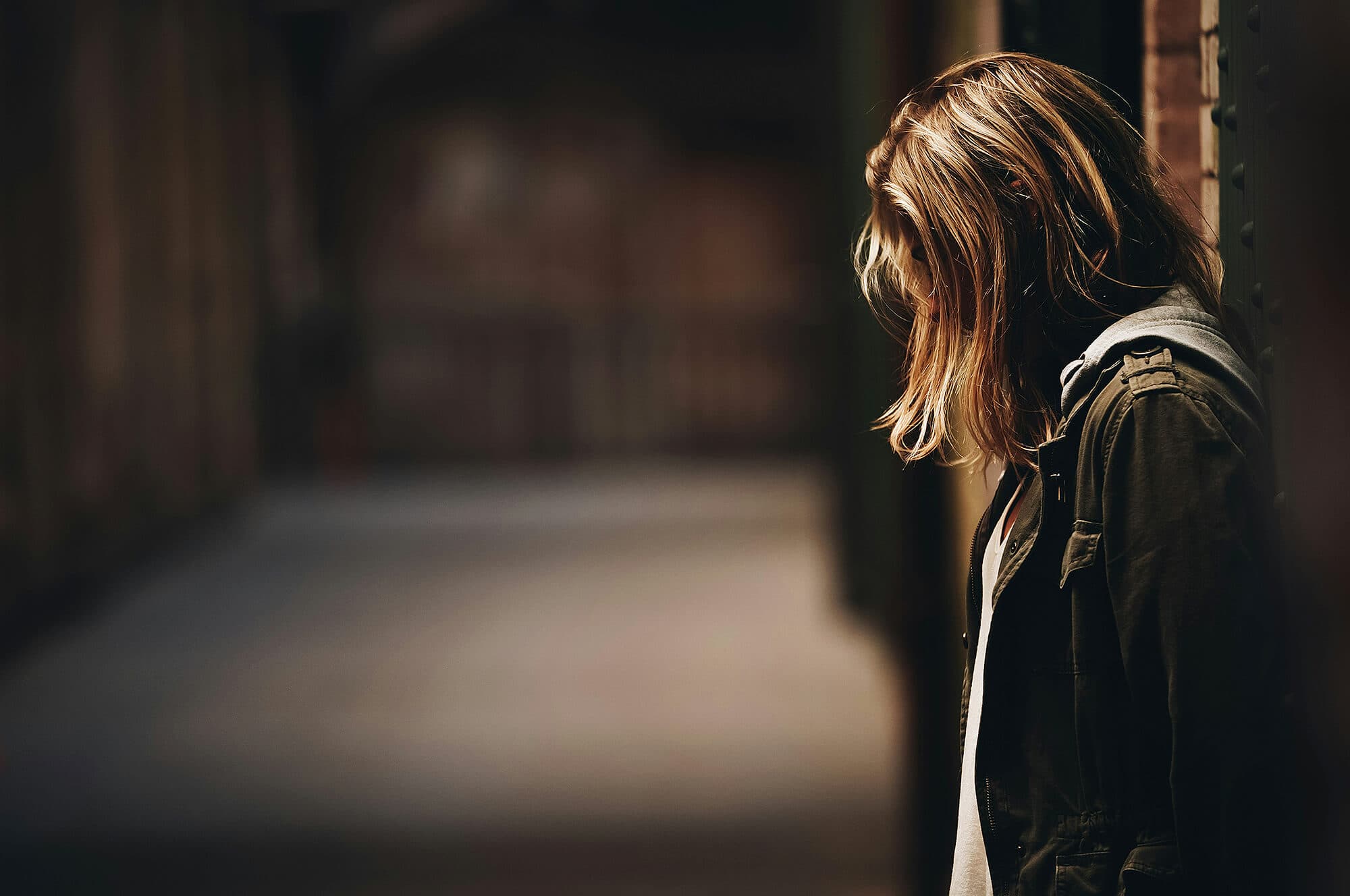 Young person in an alleyway looking down at the ground
