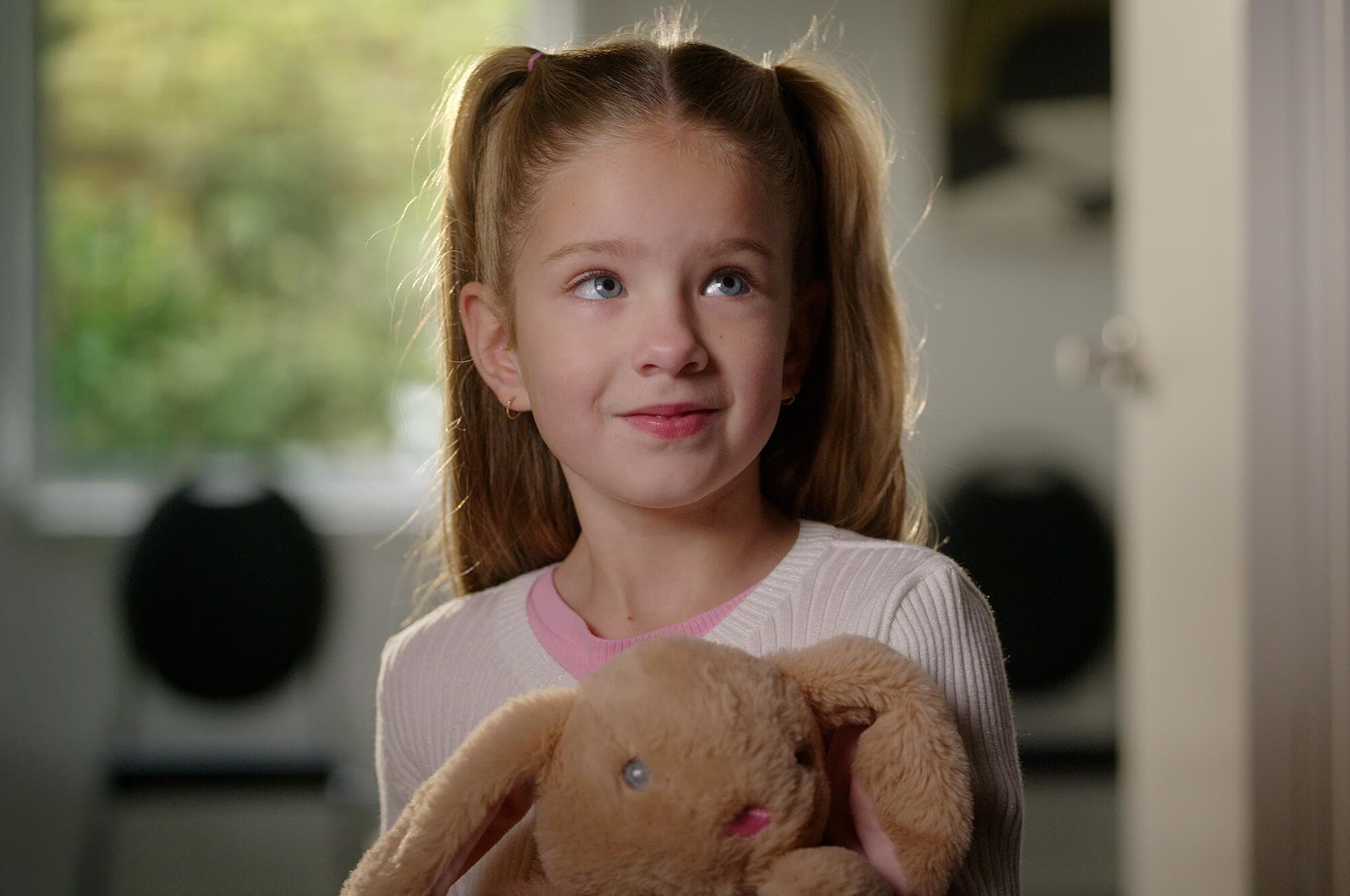Young girl holding a plush bunny while looking up