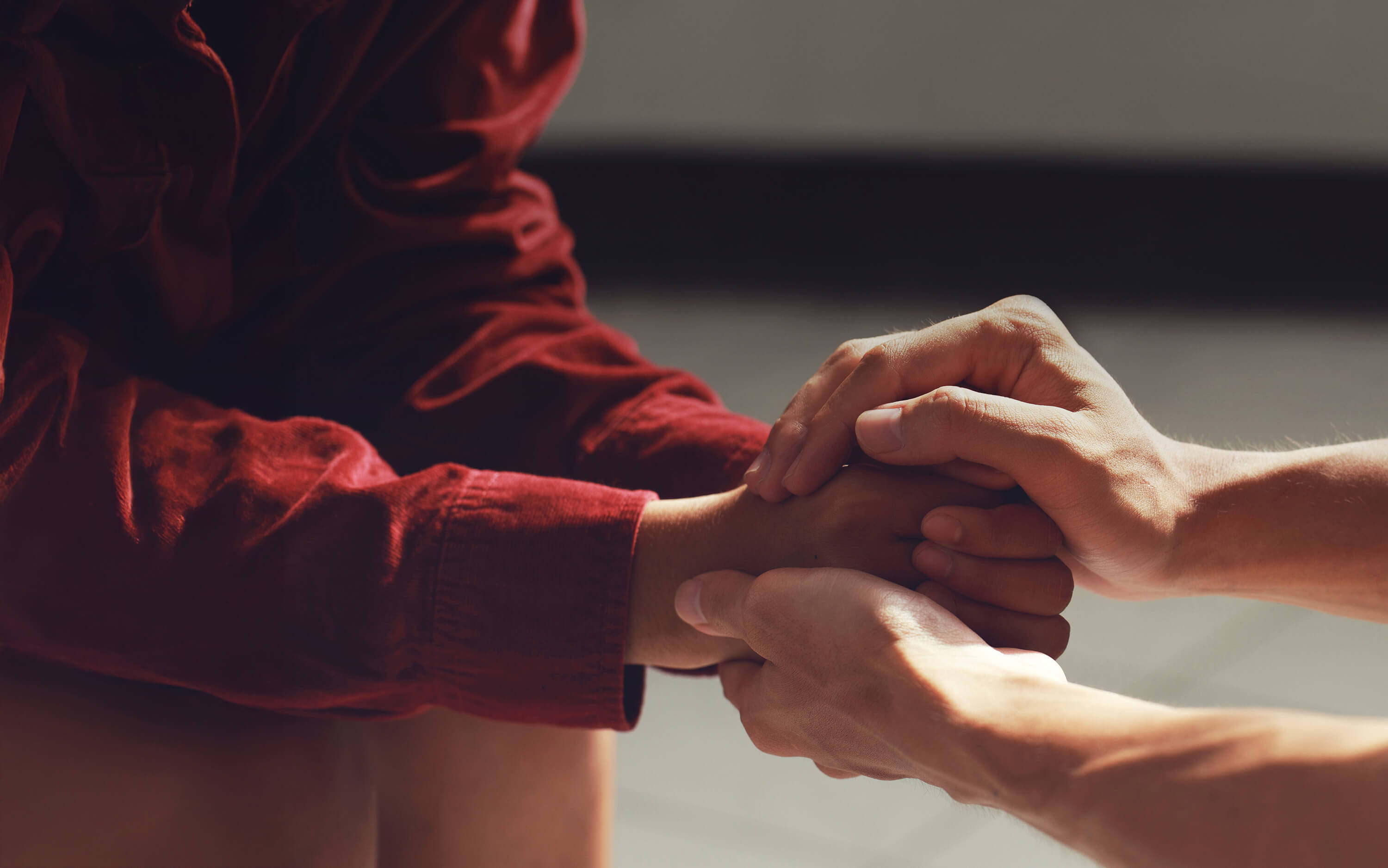 Young child sitting with hands cupped and adult hands cupped caringly over the childs