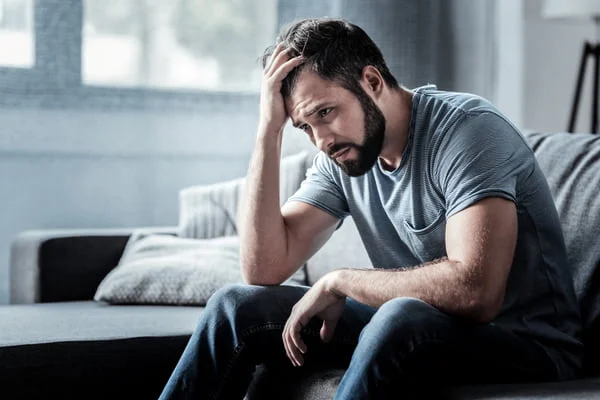 man sitting on the couch looking upset