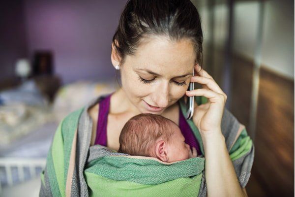 Newborn baby held by parent in the baby wrap carrier