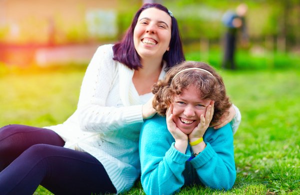 Portrait of happy women with disability on spring lawn - family support