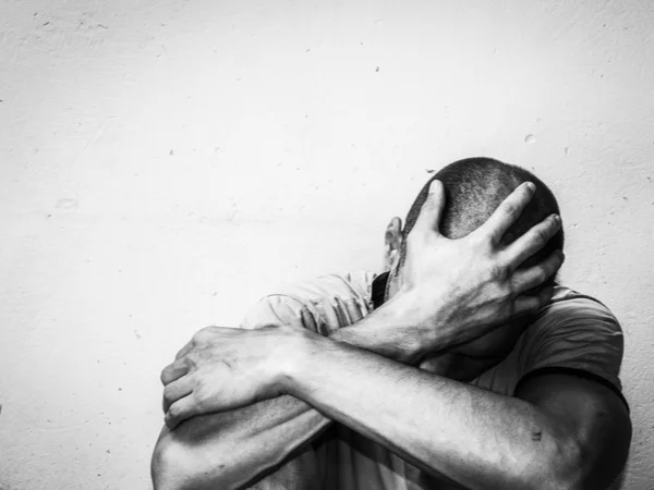 Young Person covering their head and sitting on the ground