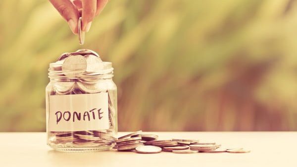Cafs-Hand-putting-Coins-in-glass-jar-with-DONATE-word Cafs-Hand-putting-Coins-in-glass-jar-with-DONATE-word
